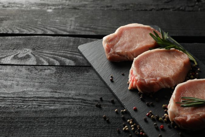 Composition with raw meat for steak and spices on wooden background