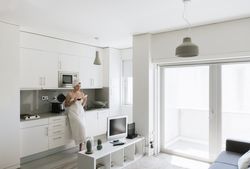Joyful adult woman enjoying day off while having hot drink after bath in apartment with simple interior design