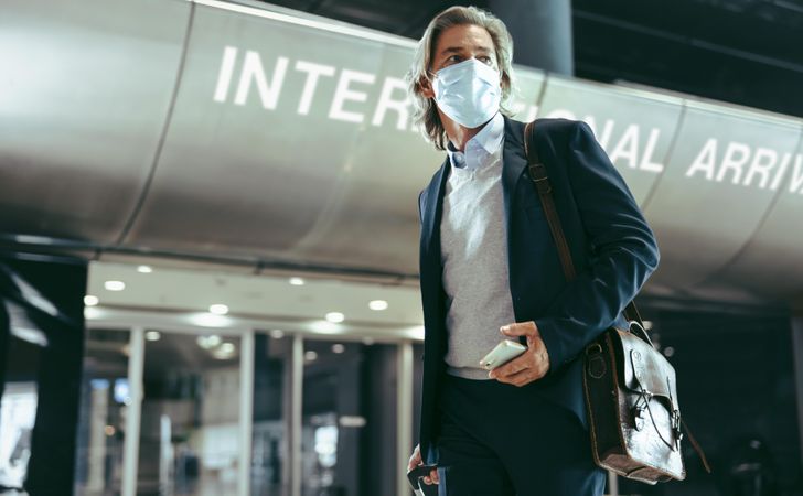 Businessman wearing face mask walking inside international airport