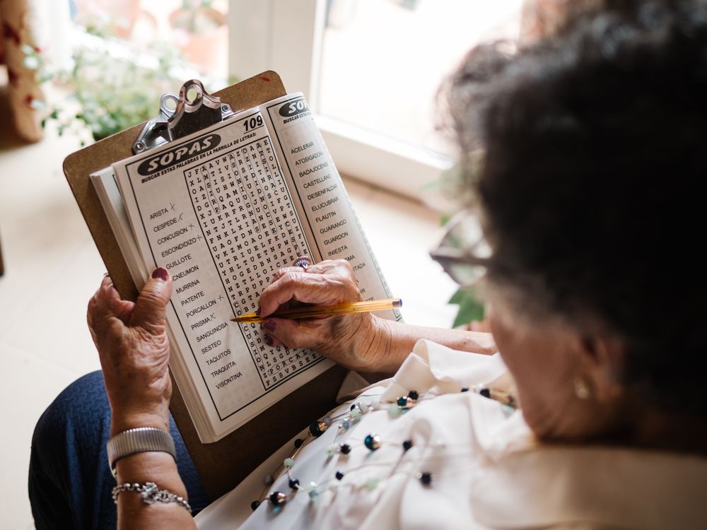 Mature woman solving crosswords in apartment
