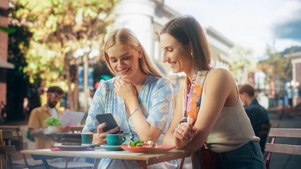 Two Young Women Relaxing on a Weekend, Sitting on an Outdoors Terrace in a Restaurant.