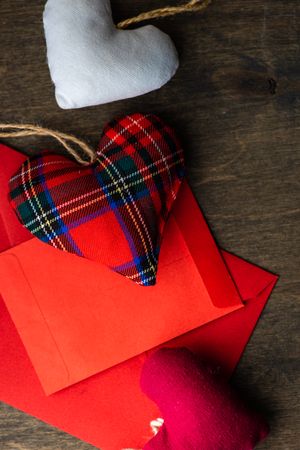 Tartan heart ornaments atop a red envelope and card