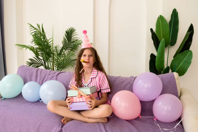 Young girl celebrating her birthday at home, holding presents.