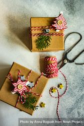 Top view of two brown Christmas presents with tree and star decorations, scissors and string 5r6kp5
