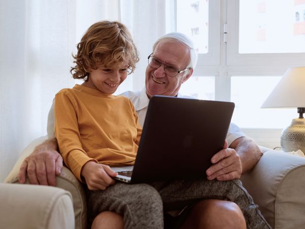 Happy boy with grandfather browsing laptop