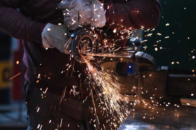 Craftsman grinding metal with grinder in vice