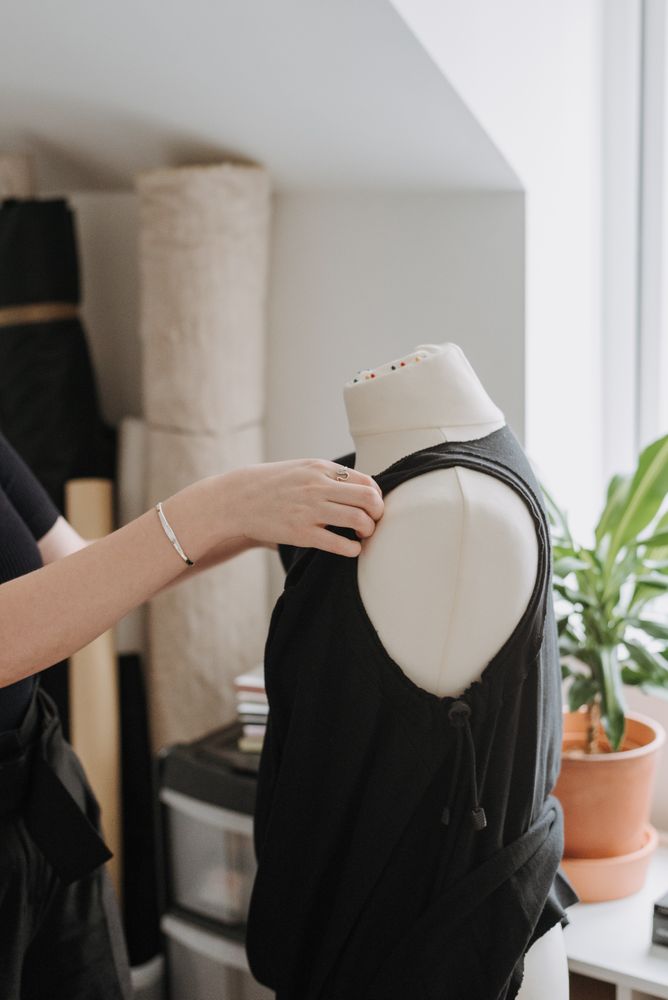 Cropped image of fashion designer dressing a mannequin with dark shirt
