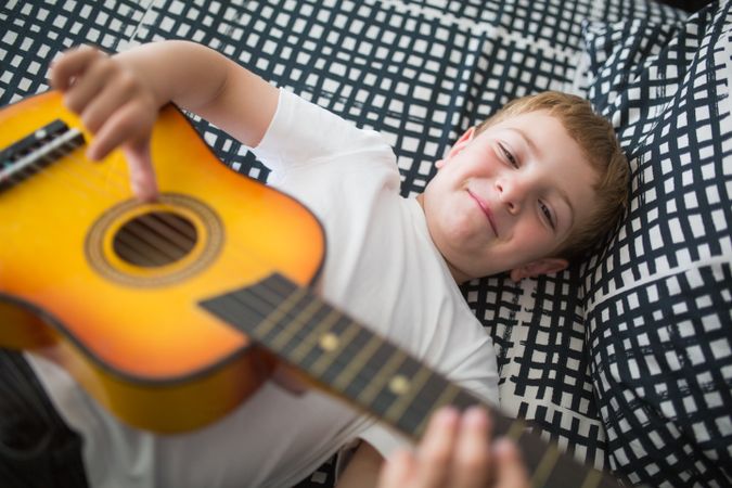 Young blonde boy playing toy guitar