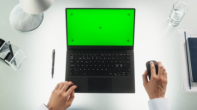 Anonymous Office Worker Typing on a Laptop Computer with Mock-Up Green Screen Chromakey Display with Motion Tracker Placeholders. Manager Corresponding with Business Partners by Email. Top Down View