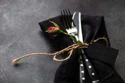 Silverware in matching napkin on counter with copy space and flower
