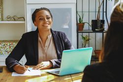 Happy woman business owner taking notes in a meeting with colleague in bright office
