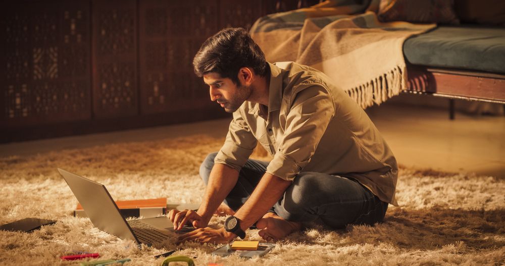 Focused Indian Man Studying at Home: Engaged in Learning, Researching, and Project Management.