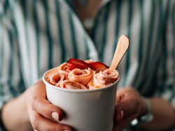 Hand holding rolled ice cream in cone cup