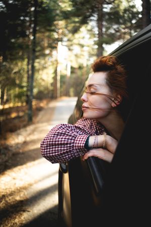 Peaceful traveler looking out of car window during trip