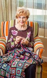 Mature woman knitting a wool quilt with patches