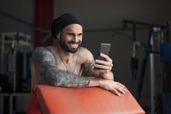 Laughing athlete with smartphone in gym