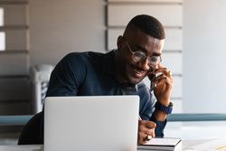 Black man talking on phone near laptop in office