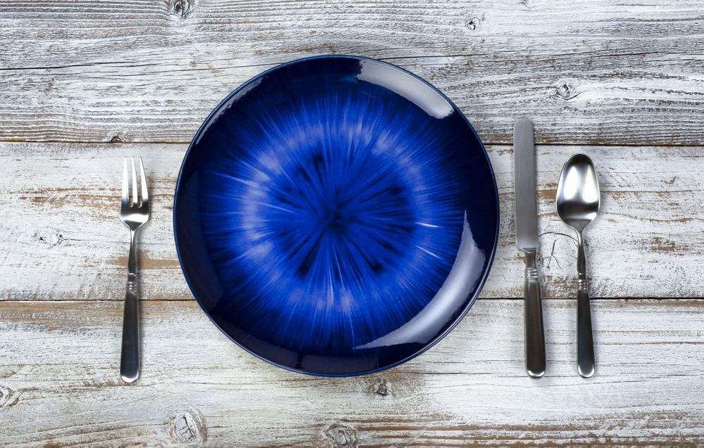 Table setting with vintage cutlery, empty blue plate, fork, spoon and knife on rustic wood table