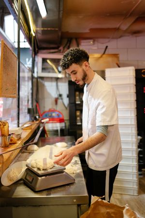 Pizza man weighing the dough on a scale