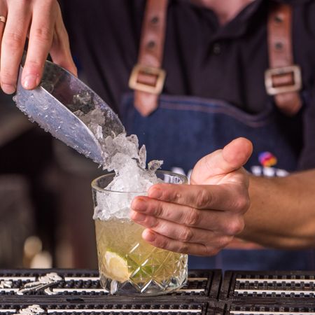 Bartender adding crushed ice to Caipirinha