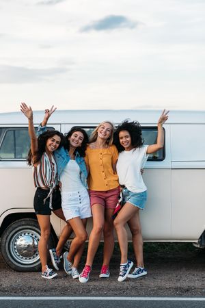 Multi-ethnic group of friends post outside a van, vertical
