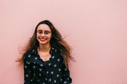 Smiling young woman against pink wall