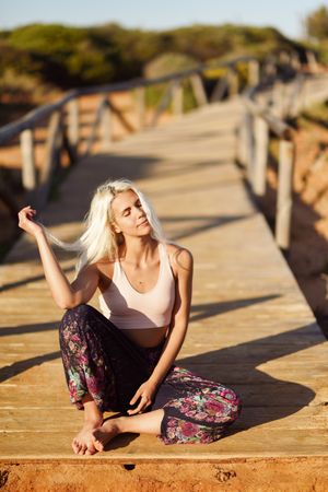 Blonde woman sitting on wooden bridge
