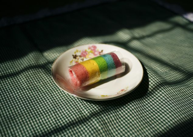 Multicolored roll on a floral plate in early sunlight