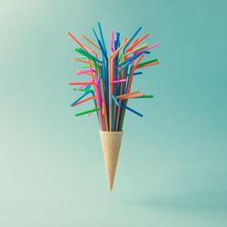 Ice cream cone with straws on light blue background