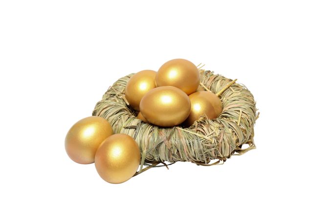 Concept of wealth and retirement - golden eggs, isolated on light background