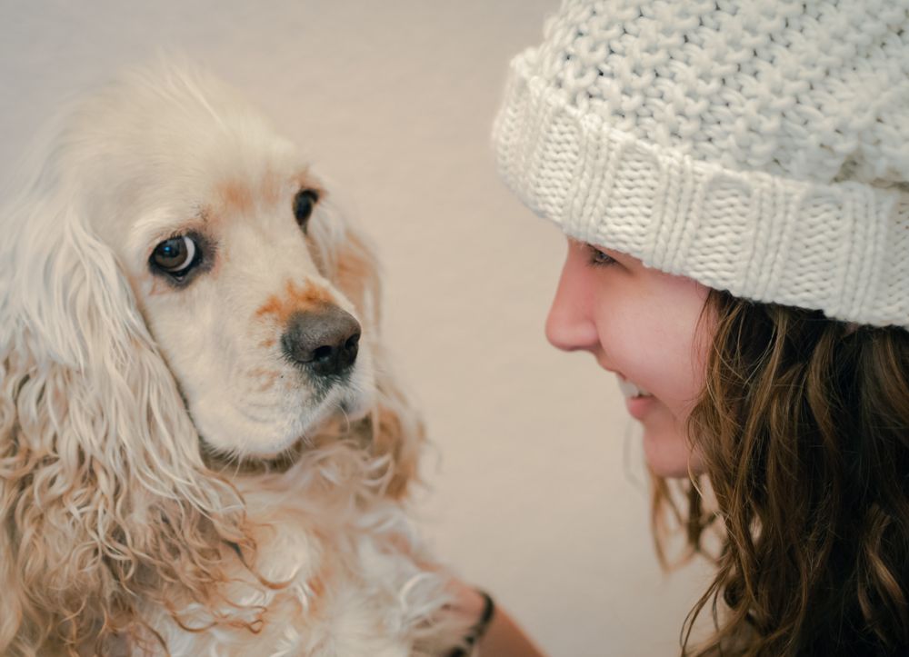 Teen in hat playing with dog