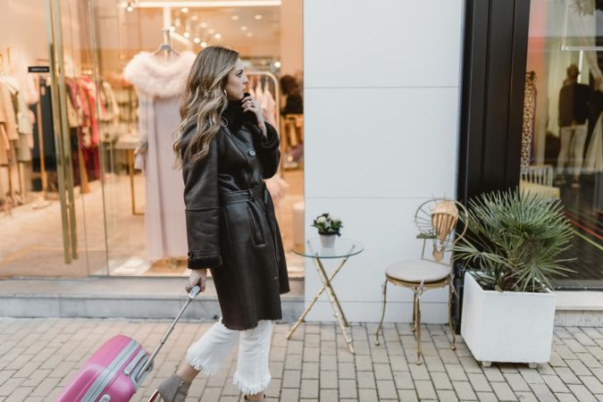 Woman with suitcase walking on street