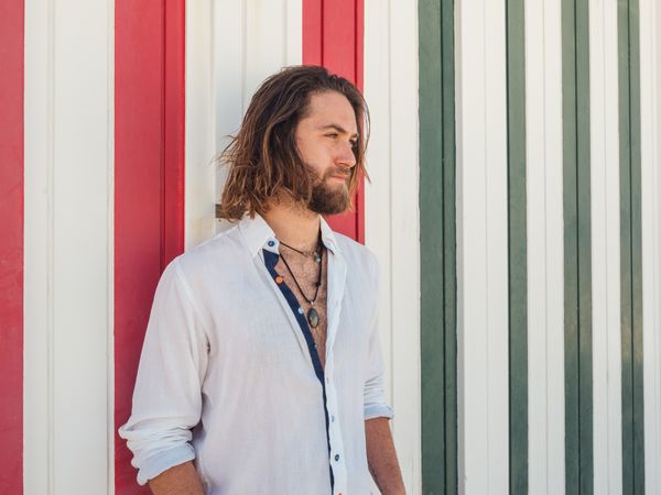 Cheerful guy standing near striped wall