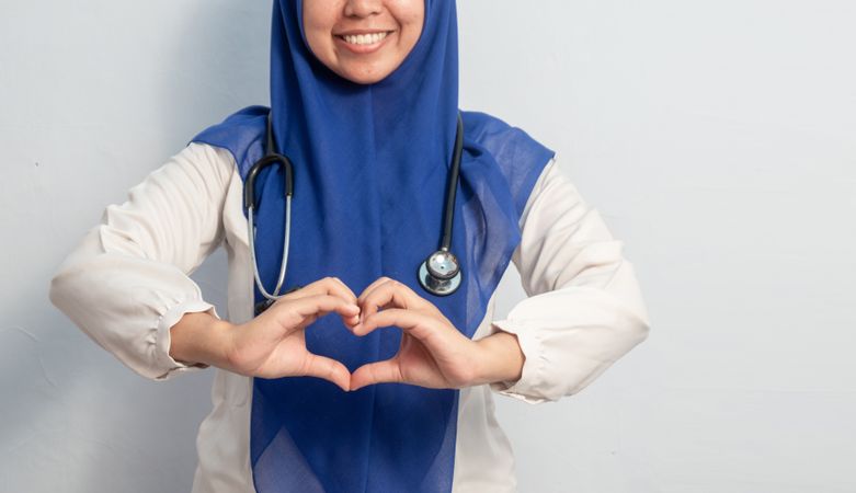 Muslim Female asian doctor or nurse with hand in love or heart symbol.