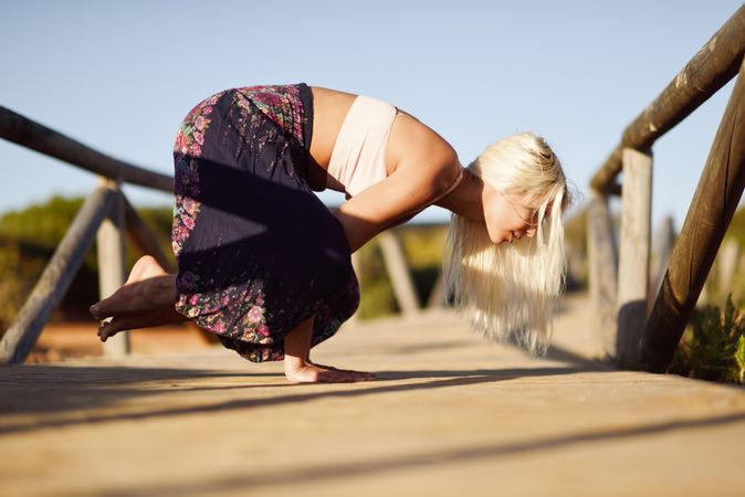 Woman in yoga pose on wooden bridge