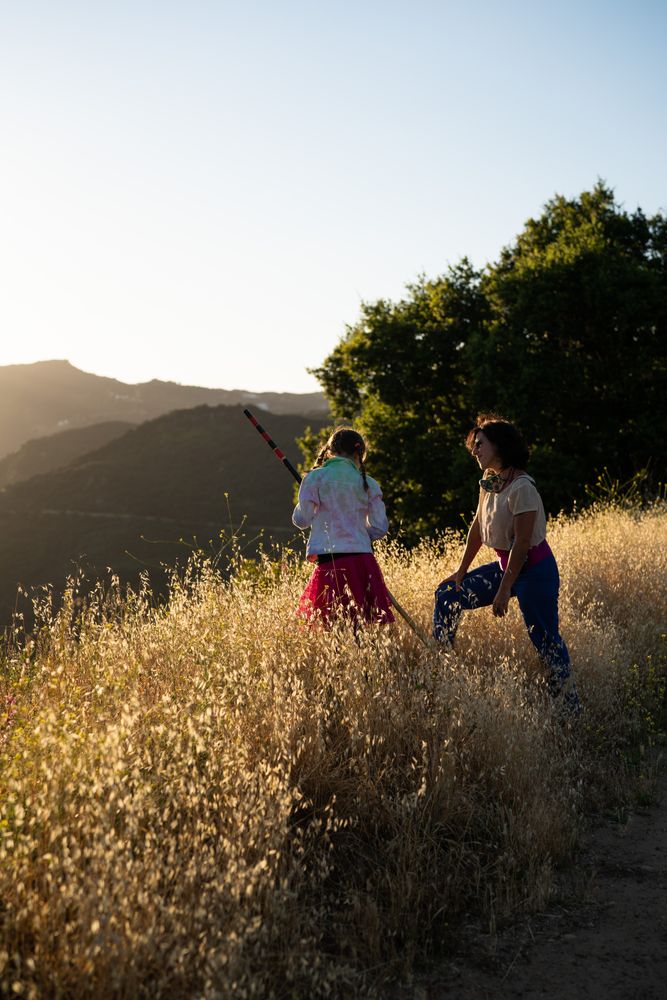 Mother looking at her daughter with love while standing in the grass on a mountain