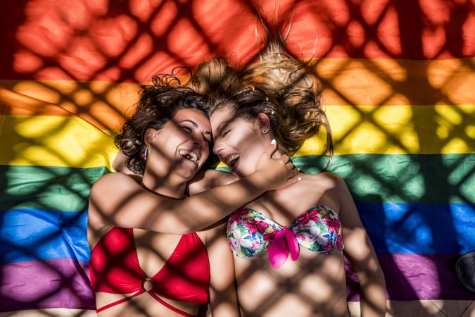 Lesbian couple lying on rainbow flag