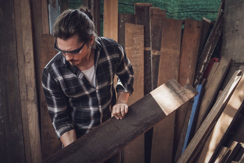Male carpenter checking quality of the wood board before making furniture at the carpentry workshop