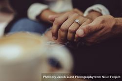 Man holding woman’s hand wearing engagement ring 4MqAE4