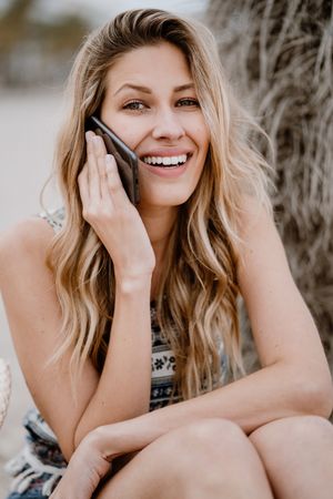 female talking on smartphone on beach