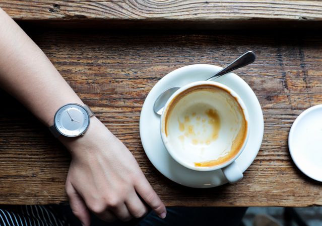 Faceless person with empty coffee cup in cafe