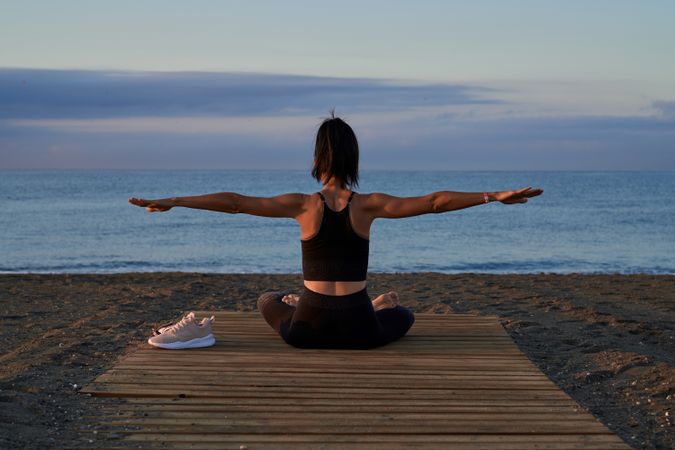 Anonymous woman doing yoga on beach