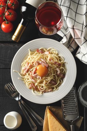 Composition with plate of tasty pasta and ingredients for cooking on wooden background