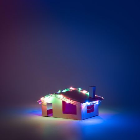 Paper house with festive lights on lit blue dark background