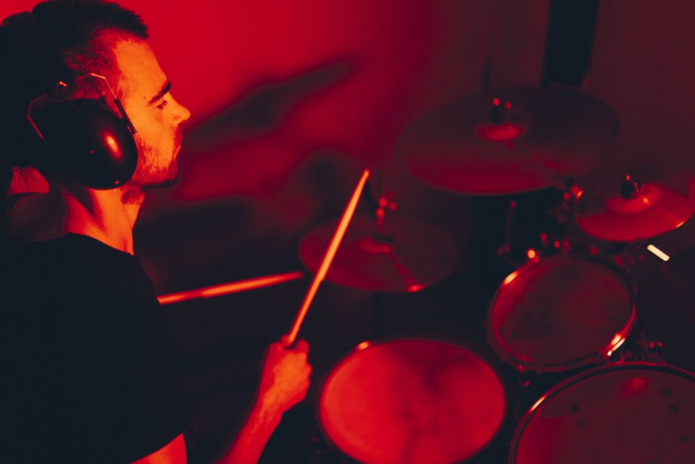 Man with drumsticks playing on drums in redness