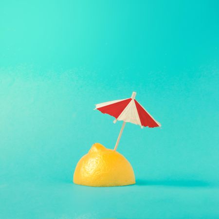 Lemon half with parasol on bright blue background