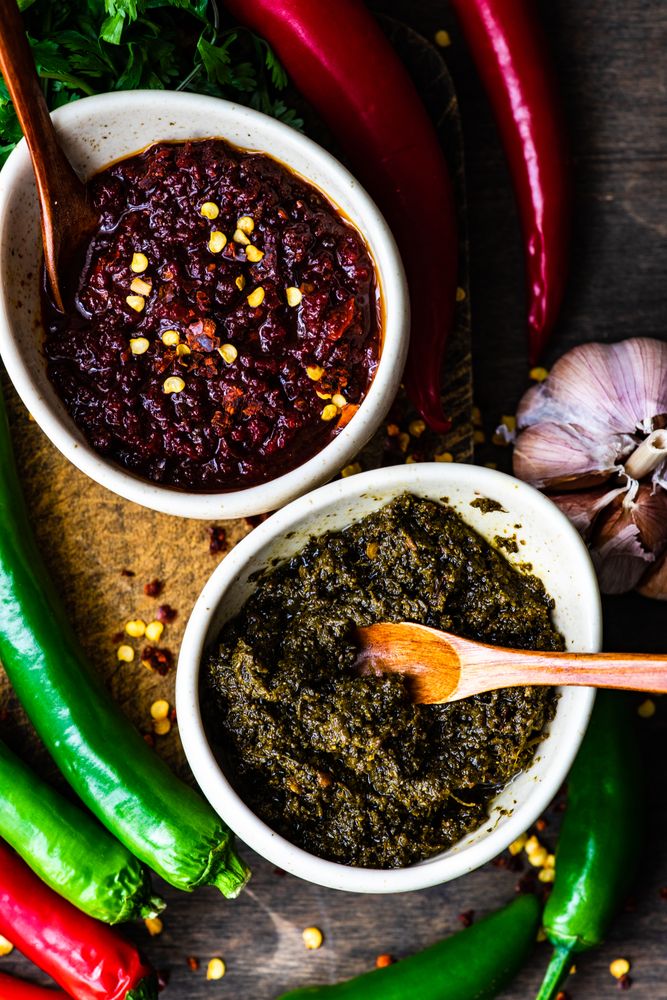 Close up of two rustic pots of traditional Georgian sauce Adjika with garlic bulb