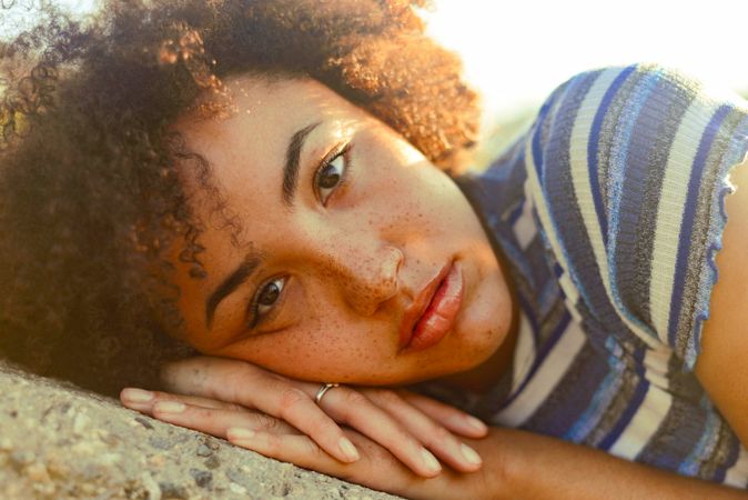 Woman with freckles and curly hair laying on rock