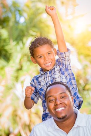 Black Son Celebrating With Father Outdoors