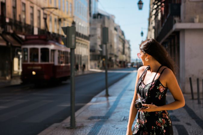 Woman holding a camera while standing on street